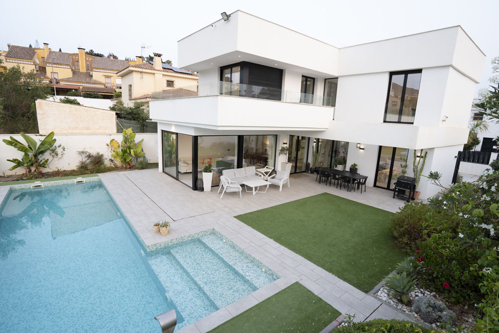 a pool and a house with a lawn and chairs
